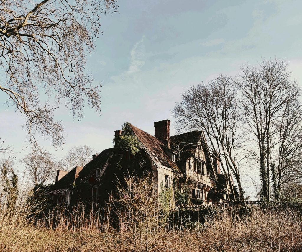 Abandoned rural house in Angervilliers, France with bare trees under a clear sky.